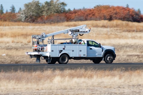 Utility company's cherry picker bucket truck driving along a rural section of interstate freeway