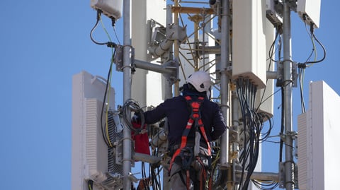 Worker performing maintenance on a 5g cellular tower, ensuring telecommunications infrastructure is functioning
